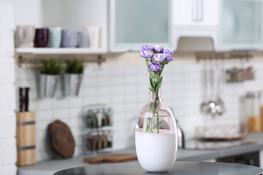 Vase with beautiful flowers on table in kitchen interior