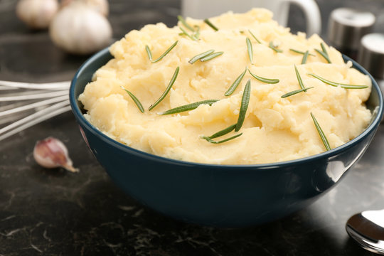 Bowl with tasty mashed potato on dark table