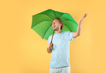 Man with green umbrella on color background © New Africa