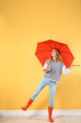 Woman with red umbrella near color wall