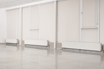 Empty spacious room with heating radiators against closed windows