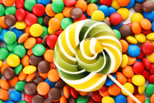Lollipop and colorful candies as background, top view