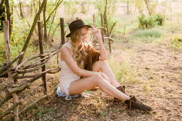 Beautiful young girl with blond hair in a suede jacket with fringed and black felt hat in the...