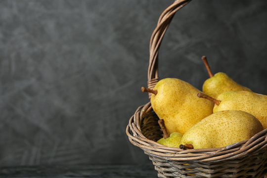 Basket of fresh ripe pears against gray background with space for text