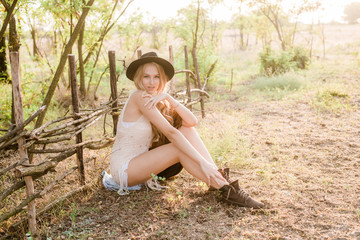 Beautiful young girl with blond hair in a suede jacket with fringed and black felt hat in the...