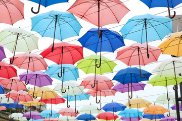 Fototapeta na wymiar Many opened multicolored umbrellas on light background