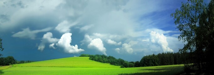 Plakat Scenic landscape with storm cloud in background over green agriculture fields