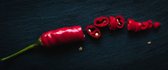 Chopped red chili pepper on dark background, top view