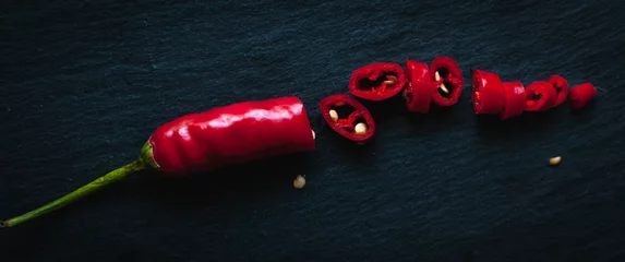 Poster Gehakte rode chili peper op donkere achtergrond, bovenaanzicht © Nevena