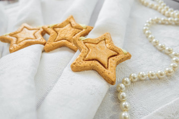 Decorative golden stars handmade from dough on a white fabric surface. Selective focus.
