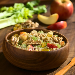 Quinoa Waldorf Salad with apple, celery, yellow raisins and walnut in wooden bowl, ingredients in...
