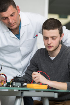 apprentice in electronics doing a voltage test