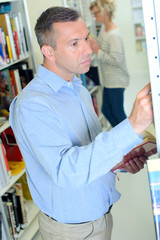 Man browsing books on library shelf