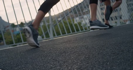 group of runners feet running friends exercise together in urban city at sunrise doing competitive workout multi ethnic athletes training close up slow motion