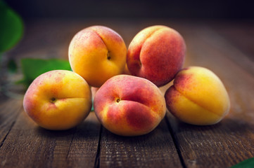 Ripe fresh apricots and apricot leaves on a wooden background. Selective focus, healthy eating