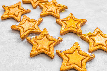 Two rows of eight decorative golden stars handmade from dough on a bright white fabric surface. Limited depth of field.