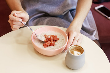 The girl has Breakfast oatmeal porridge and coffee in the cafe