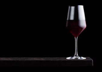 Fotobehang Glass of red wine on wooden board on black background. Space for text © DenisMArt