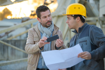 workers colleague looking at phone outdoors