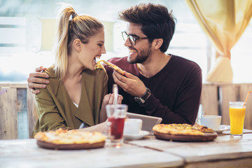 Smiling couple enjoying in pizza, having fun together. - obrazy, fototapety, plakaty