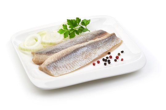 Fillet of salted marinated Atlantic herring with onion, peppercorns and parsley, isolated on white background.