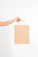 Template blank package. African american woman hand holding a paper kraft bag isolated on white...