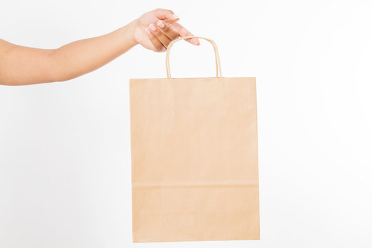 Template Blank Package. African American Woman Hand Holding A Paper Kraft Bag Isolated On White Background. Delivery And Shopping Concept.