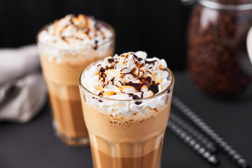 Iced latte coffee in a tall glass with caramel and chocolate syrup and whipped cream.