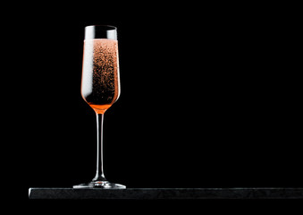 Elegant glass of pink rose champagne with bubbles on blavk marble board on black background. Space for text