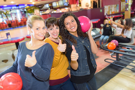Women with thumbs up in bowling hall