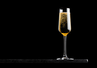 Elegant glass of yellow champagne with bubbles on blavk marble board on black background. Space for text