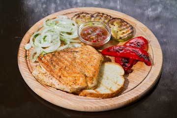 Grilled chicken meat with pickled onions and zucchini, paprika, served on wooden plate, delicious food photo