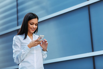 Young business woman reading a message on the smartphone outdoors