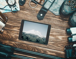 Mount Elbrus on screen of tablet among travel equipment.