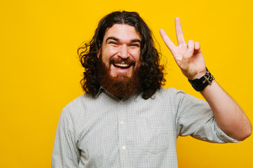 Happy man with beard showing two fingers, peace sign