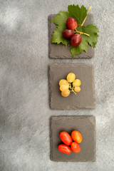 bunches of grapes and cherry tomatoes on slate squares