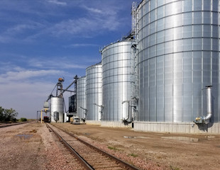 Fototapeta na wymiar bright shinning metal grain elevators next to railroad tracks, Wall, SD, USA