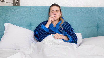 Portrait of young sick woman with runny nose using nasal spray