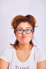 Fototapeta premium The girl with glasses clasped her lips and looks with cunning eyes