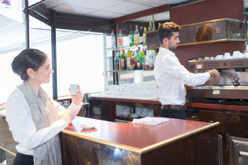 Fototapeta na wymiar young male barista serving cup of coffee to customer