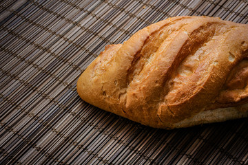 bread on the table just from the stove. freshly baked loaf of bread on a straw mat.