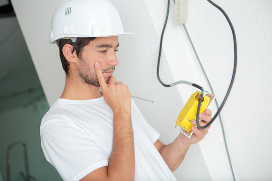 young man installing socket on wall at home