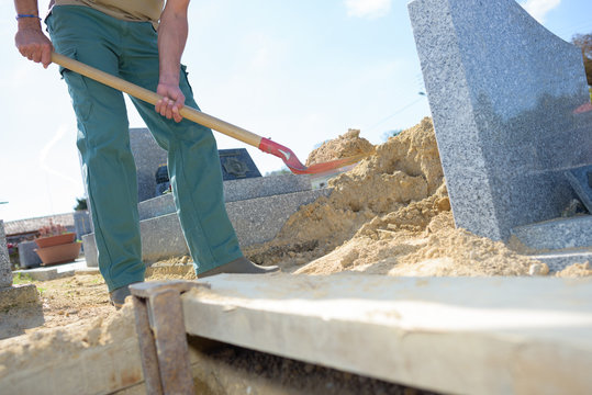 Man filling in grave with sand