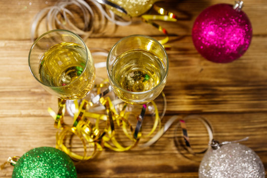 Two glasses of champagne and festive Christmas decorations on wooden table. Top view. Christmas and New Year celebration