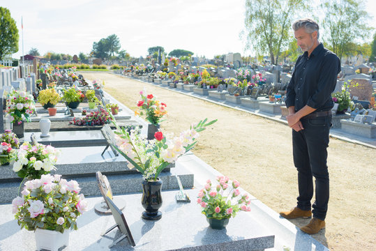 Man stood alone looking at grave