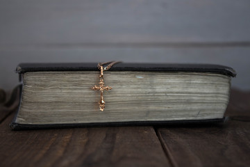 a bible and golden cross on wooden background