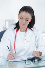 portrait of young female doctor sitting at desk in hospital