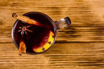 Cup of mulled wine with cinnamon on wooden table. Top view