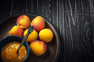 Ripe fresh apricots and apricot jam on a wooden background. Selective focus, healthy eating