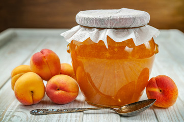 Ripe fresh apricots and apricot jam in a jar on a wooden background. Selective focus, healthy eating